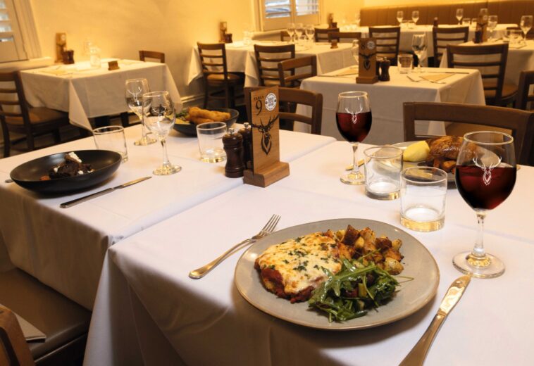 Family dining table with chicken parmigiana, roast meal, and red wine at a pub restaurant